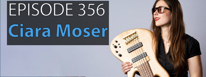 Ciara Moser, a woman in her 20s with long brown hair and wearing sunglasses, smiles as she holds a bass guitar.